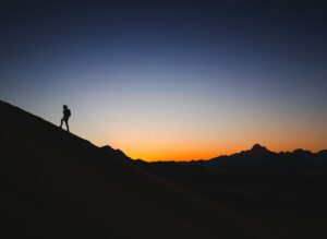 Man walking uphill away from sunset