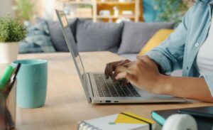 Hands on a laptop computer with a coffee cup nearby